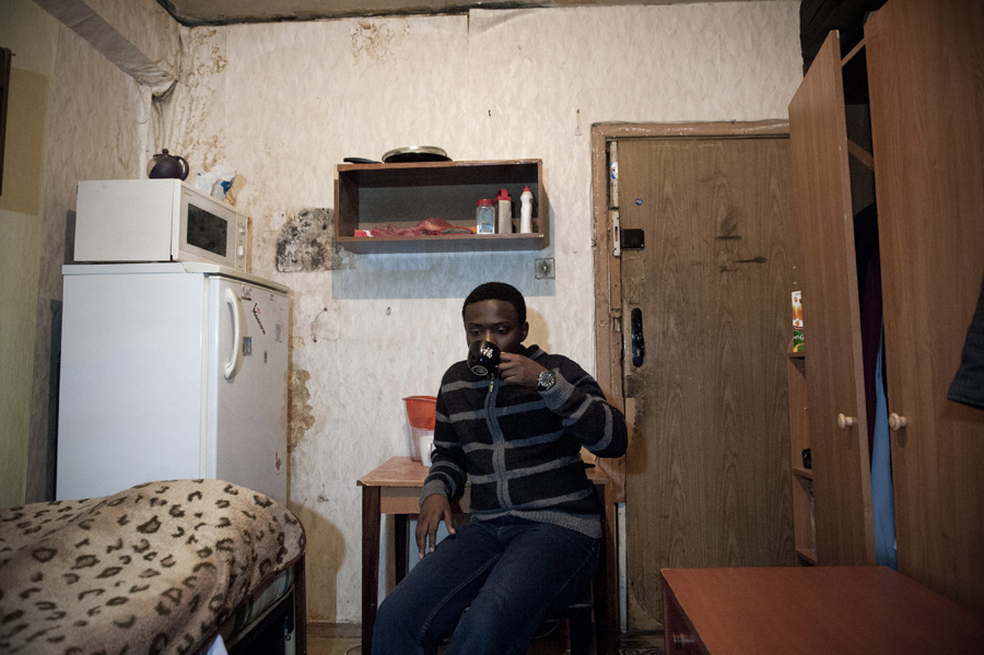 Kudakwashe Ndlova, a 25-year-old student from Zimbabwe, drinking tea in a room he shares with a Russian student.